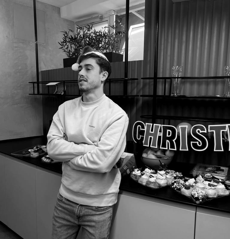 A colleague in a Santa hat standing beside the office Christmas dessert spread